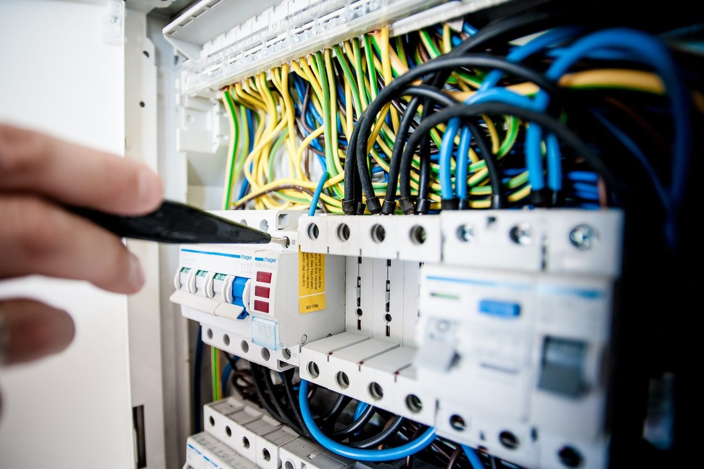 Ranka su matuoklio zondu prie automatinių jungiklių elektros skydelyje