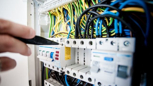 Ranka su matuoklio zondu prie automatinių jungiklių elektros skydelyje